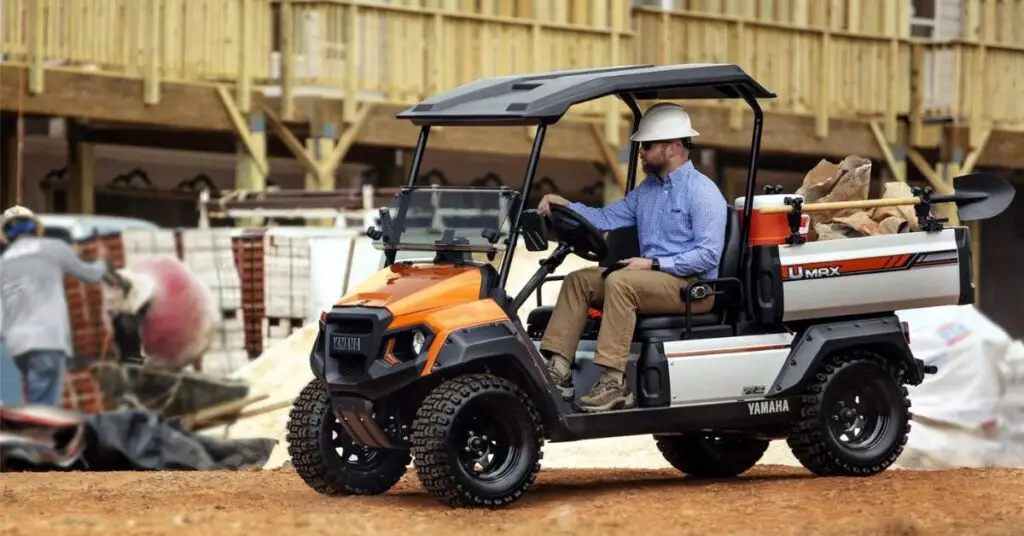 A person driving a Yamaha UMAX Rally gas golf cart on a construction area.